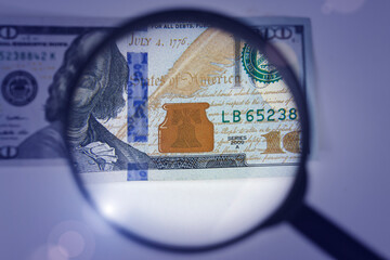 Magnifying glass on dollar banknotes. Hundred dollars banknote authentication. Inspecting a Hundred Dollar Bill.