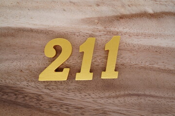 Golden Arabic numerals on real wood with brown and white pattern.