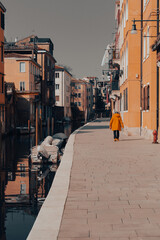 Fototapeta premium Small Venetian side street with a passer-by wearing a yellow jacket.