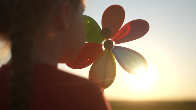 kid pinwheel. little baby girl silhouette play with windmill toy wind in the park. happy family kid dream concept. baby fun girl play toy pinwheel the glare sunset of the sun at in the park