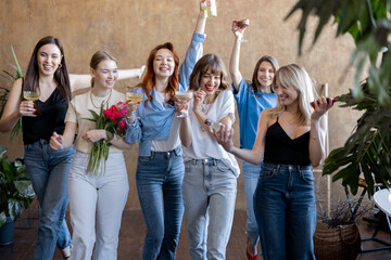 Young girlfriends having fun together, walking with flowers and drinks. Celebrating women's day or having hen-arty. Concept of female friendship and beauty. Women with different hair color wearing