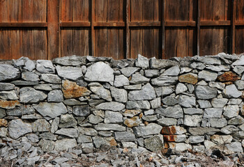 Limestone fence wall with vintage wooden background.