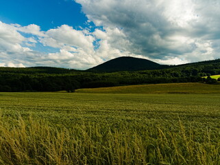 Fototapeta premium Cultivated fields on a background of mountains. Fields under cloudy skies. Mountain landscape