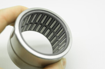 Needle bearing in hand. Roller bearing for motors, machinery and equipment. Spare part. Selective focus, isolated on white