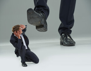 Trampled by The Man. Cropped view of a businessman crouched as a giant shoe comes down on him. © T Hover/peopleimages.com