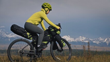 The woman travel on mixed terrain cycle touring with bikepacking. The traveler journey with bicycle...