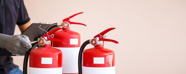 Fototapeta premium Close up fire extinguisher and firefighter checking pressure gauge level for protection and prevent and safety rescue and use of equipment on fire training concept.