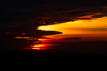Obraz premium Mountains in clouds at sunrise in summer. Aerial view of mountain peak in fog. Beautiful landscape with high rocks, forest, sky. Top view from drone of mountain valley in low clouds. Foggy hills 
