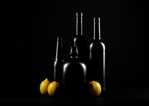 czarne butelki z żółtymi cytrynami na czarnym jednolitym tle