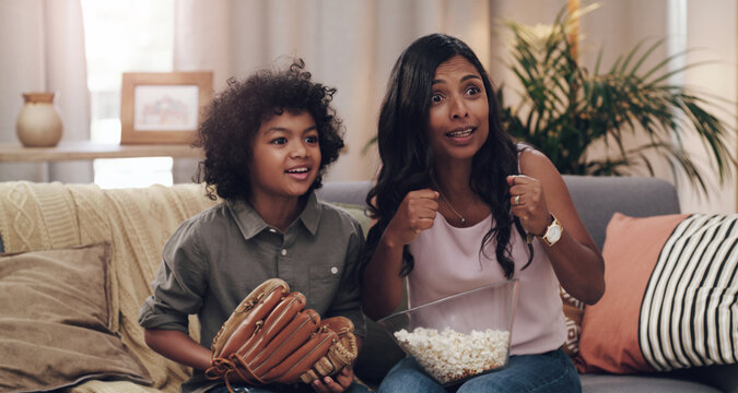 This Match Has Us At The Edge Of Our Seats. Shot Of An Adorable Little Boy Watching A Baseball Game With His Mother On Tv At Home.