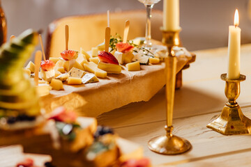 Naklejka na ściany i meble Cheese selection on wooden rustic board. Cheese platter with different cheeses, grapes, nuts, honey and dates on weathered wood background.