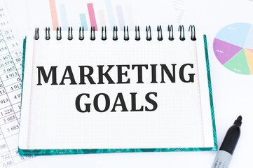 Marketing Goals inscription on notepad on the background of charts and reports