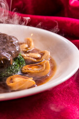 braised vegetable broccoli with mushroom and premium abalone in soy stock sauce cinese banquet menu on red cloth background