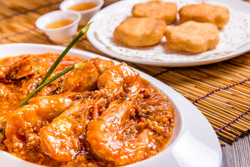 stir fried prawn seafood with spicy chilli crab egg thick gravy sauce and deep fried man tofu bun on bamboo wood table tea pot asian Chinese halal food restaurant banquet cuisine cafe menu
