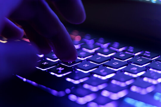 Working on a neon computer keyboard with colored backlighting. Computer video games, hacking, technology, internet concept. Selected focus.