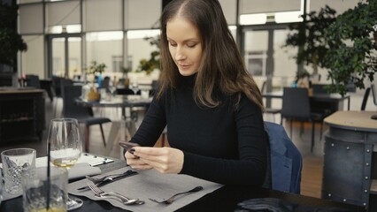 Obraz premium Happy smiling middle age woman using phone sitting in restaurant or cafe.