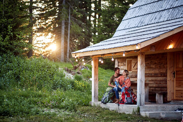 Fototapeta na wymiar A young couple in love spending time together at the cottage porch in the forest. Vacation, nature, cottage, relationship