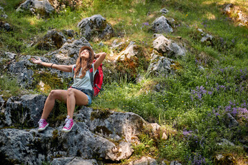 Caucasian woman sitting on rock in forest. Backpacker enjoying hike in forest. Hiking, lifestyle, nature concept