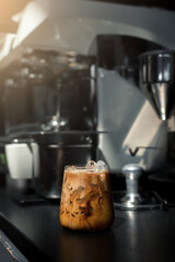 Ice coffee on a black table with cream being poured into it showing the texture and refreshing look of the drink