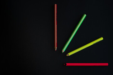 Aerial shot of colored highlighter pencils leaving copy space on black background. Fan of colored school pens on a black backdrop.