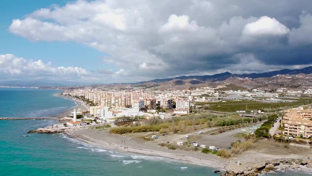 Panoramic aerial view of beautiful costal city Torrox. Drone going left creating a beautiful  perspective of Torrox Costa. View of the lighthouse of Torrox,  river and promenade of Torrox. 
