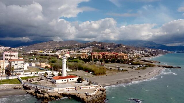 Panoramic aerial view of beautiful costal city Torrox. Drone going backward creating a beautiful  perspective of Torrox Costa. View of the lighthouse of Torrox,  river and promenade of Torrox. 