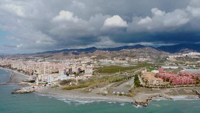Panoramic aerial view of beautiful costal city Torrox. Drone going backward creating a beautiful  perspective of Torrox Costa. View of the lighthouse of Torrox,  river and promenade of Torrox. 