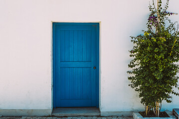 Entrance door of blue color in a white wall.