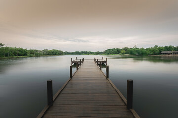 Fototapeta premium The wooden bridge stretches into the middle of the water. In the beautiful nature, evening