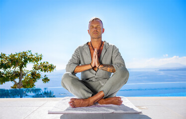 Fototapeta na wymiar Man meditating on terrace with beautiful sea view