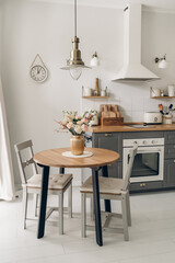 Spring bouquet on wooden table in the kitchen. Scandinavian style. White wooden background. Bright kitchen interior