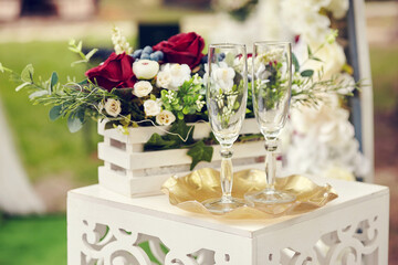 Glasses of wine stand on a table decorated with red and white flowers