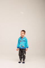 
A little boy stands on a white background and smiles