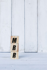 mrr concept written on wooden cubes or blocks, on white wooden background.
