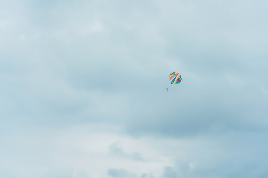 Parasailing is an extreme water attraction on the beach. Parachute flight over the sea. Parasailer on the background of a cloudy sky