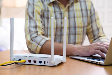 Selective focus at router. Internet router on working table with blurred man using tablet at the...