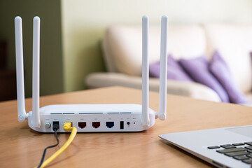 Selective focus at router. Internet router on working table with living room no people at the background. Fast and high speed internet connection from fiber line with LAN cable connection.