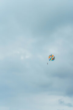 Parasailing is an extreme water attraction on the beach. Parachute flight over the sea. Parasailer on the background of a cloudy sky
