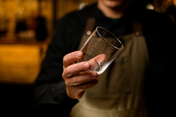 Beautiful empty glass for drink in hand of male bartender