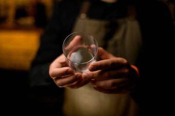 hands of bartender accurate hold cocktail glass. Focus on the fingers