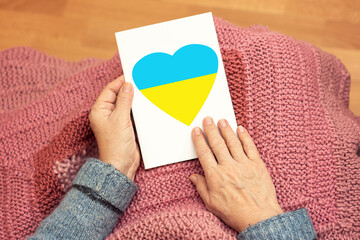 Top view of an adult woman grandmother holding a card in her hands with a heart symbol in the color...