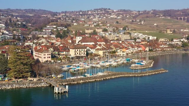 Aerial drone footage of the Lutry village and Marina in the Lavaux area near Lausanne by the lake Geneva on a sunny day in Switzerland. Shot with a rotation motion