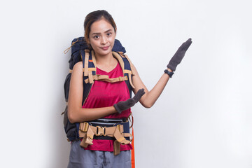 Young asian hiker woman with backpack pointing finger on empty space on white background
