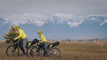 The man and woman travel on mixed terrain cycle touring with bikepacking. The two people journey...
