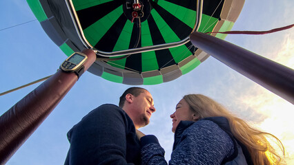 Adventure love couple on hot air balloon watermelon. Man and woman kiss hug love each other. Burner...