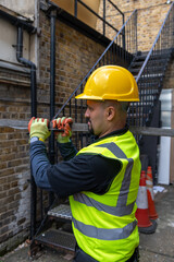 A construction working working in a building site carrying a metal bar on his shoulder.