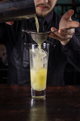 Bartender dressed in black apron and shirt make lime cocktail drink on black background