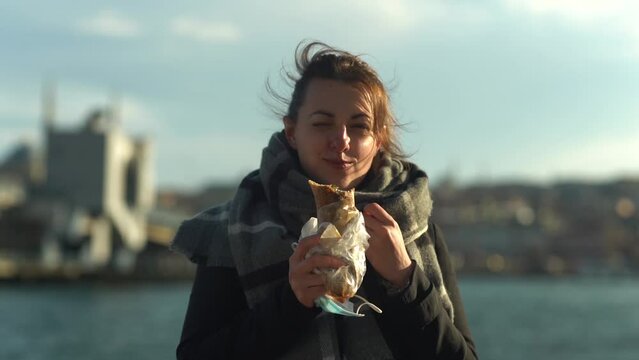 A young woman eats a kebab and smiles