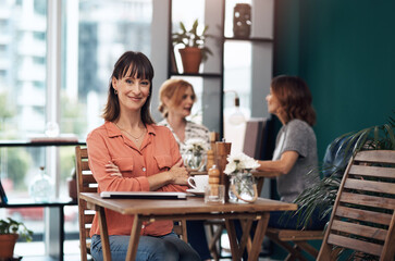 I come here every day. Portrait of an attractive middle aged woman having coffee by herself at a coffee shop during the day.