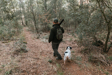 Naklejka na ściany i meble Man hunting with dog in dense forest